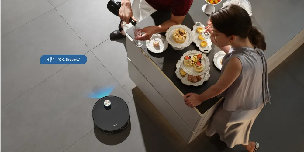 Dreame robot vacuum starting a clean on an "OK Dreame" voice command while people gather in the kitchen