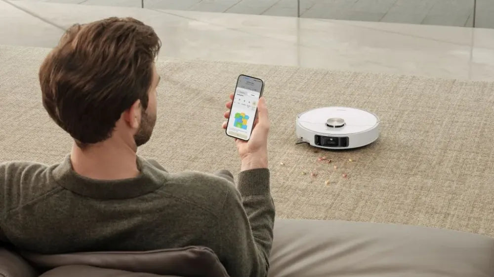 Robot vacuum on hardwood with the app open to a scheduled cleaning list.