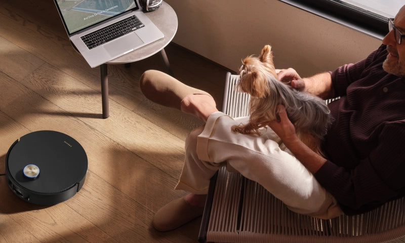 Dreame robot vacuum cleans the floor nearby and a laptop sits on a side table.